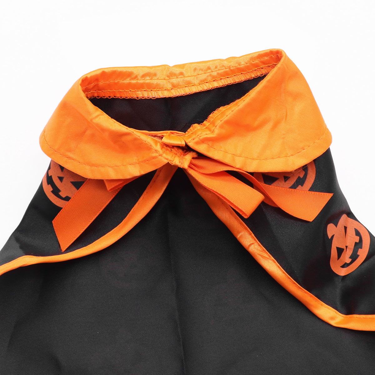 Close view of the orange satin collar of the dog cape tied into a ribbon bow at the neck