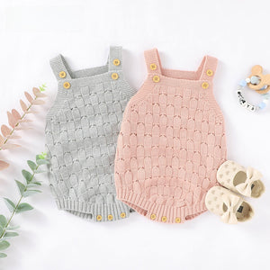 Gray and pink knitted baby rompers with wood button straps shown flat, front view
