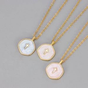 Three gold plated enamel cross pendants in pale blue, white, and blush pink shown side by side on gold chains
