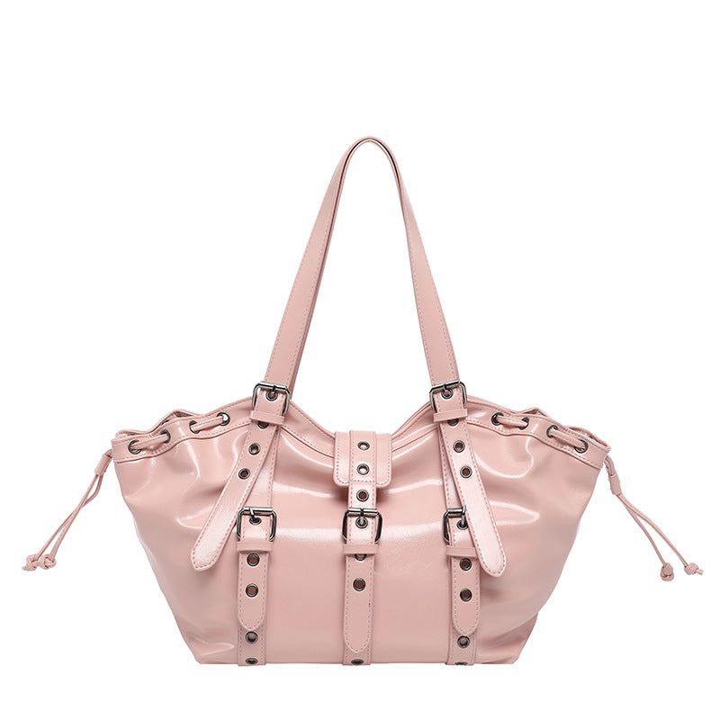Glossy pink hobo shoulder bag with buckle straps, grommets and side drawstrings on a white background