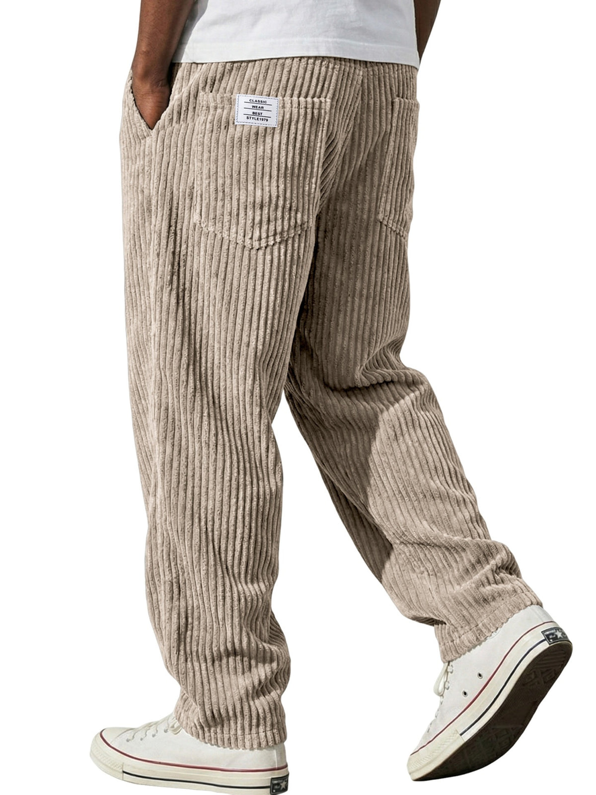 Side view of the loose straight corduroy trousers falling clean over white trainers