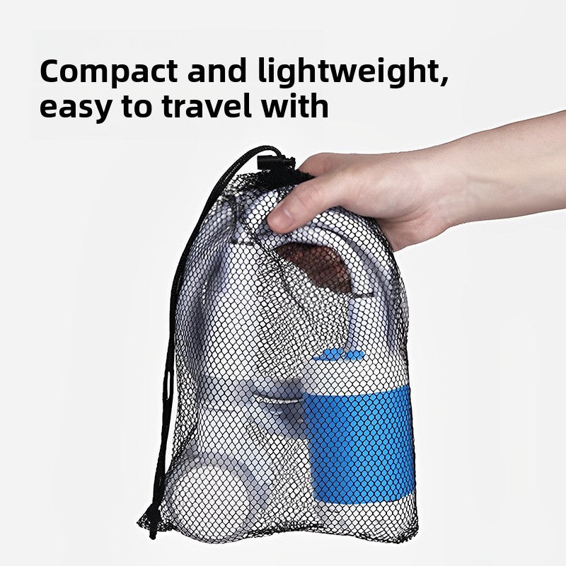 Hand holding the compact shower kit packed inside a black mesh drawstring travel bag