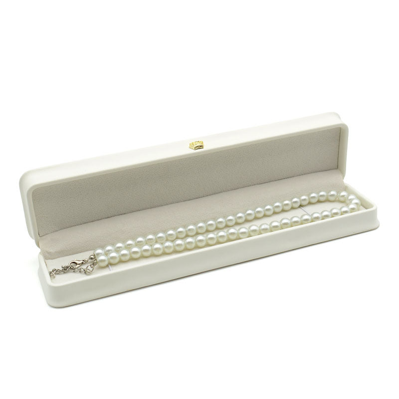 Open off white crown clasp necklace box with a pearl necklace resting on the grey lining