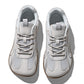 Pair of light gray mesh sneakers with a roomy round toe box and a gum brown flat sole, seen from above on white