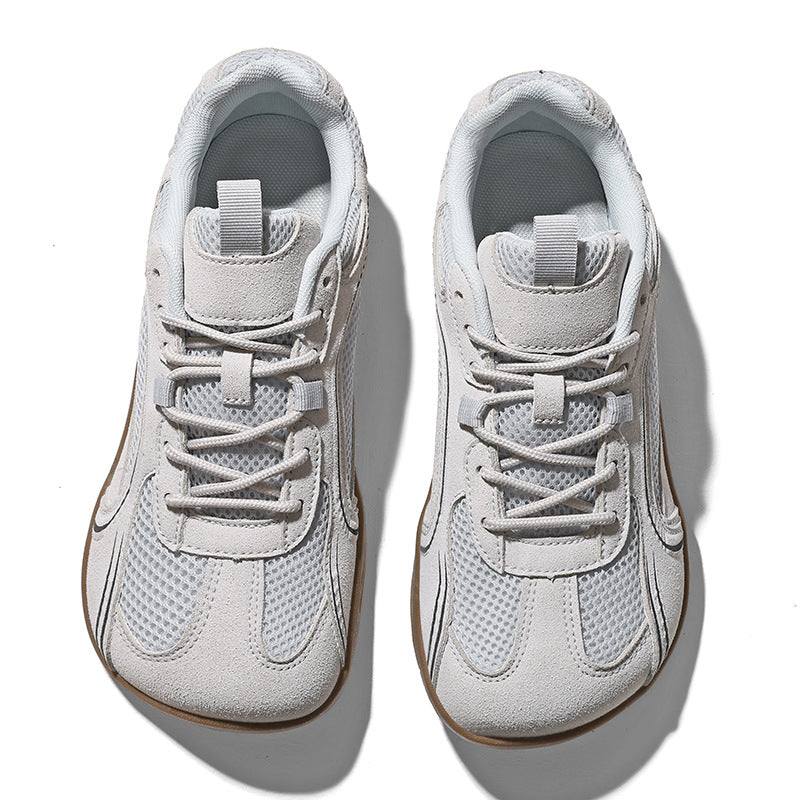 Pair of light gray mesh sneakers with a roomy round toe box and a gum brown flat sole, seen from above on white