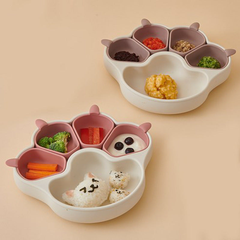 Two cream bear paw plates holding colorful food, one with four small burgundy cups, on a peach background