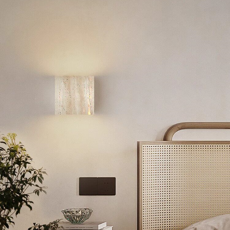 Rectangular travertine LED sconce mounted on an interior wall with warm downward glow