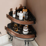 Black walnut fan shaped bathroom corner shelf mounted in a tiled corner with bottles