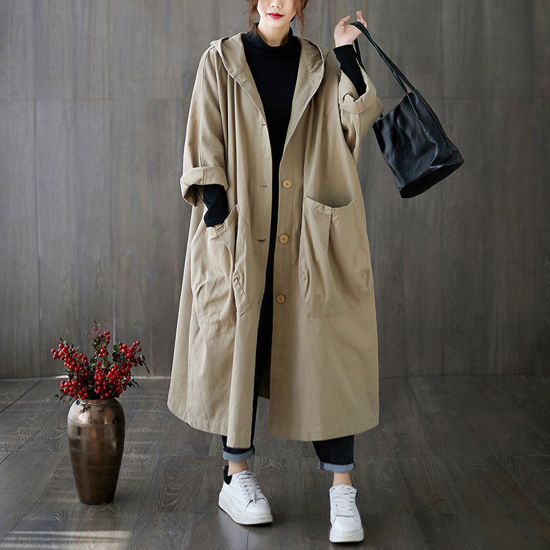 Woman wearing the loose hooded long coat layered over jeans and sneakers