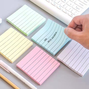 Pastel sticky note pads with horizontal ruled lines fanned out beside an open notebook