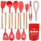 Red silicone utensil set laid out flat with turners, spoons, ladle, spaghetti server, brush, tongs, whisk and holder