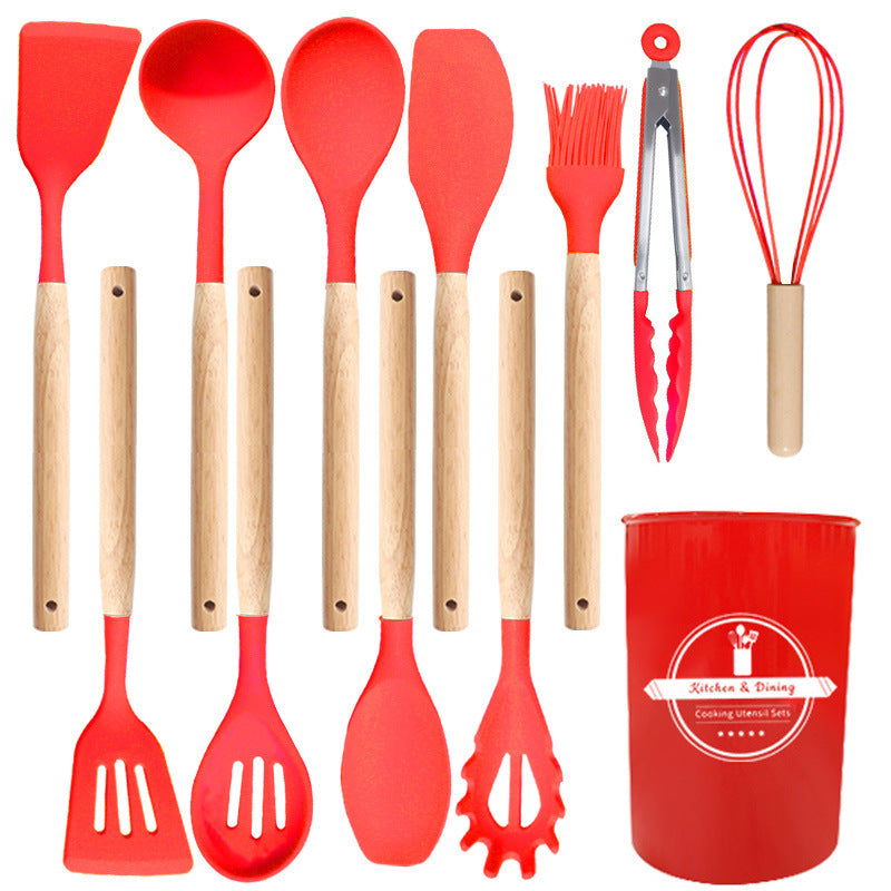Red silicone utensil set laid out flat with turners, spoons, ladle, spaghetti server, brush, tongs, whisk and holder