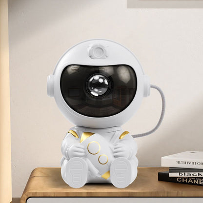 White astronaut star projector hugging a rocket, sitting on a wooden desk beside books