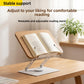 Reading stand with an open book on a wooden desk, with a plant and shelves in the background