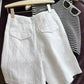White linen summer shorts high waist detail styled on a dark surface