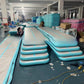 Stacks of mint green inflatable air track mats with gray tops and an air pump hose in a warehouse