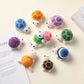 Ten hand crocheted turtles with colorful shells arranged on a cream surface beside open books