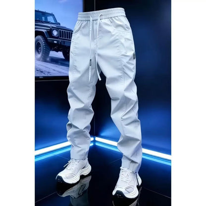White drawstring jogger pants with white sneakers on a display stage lit in blue