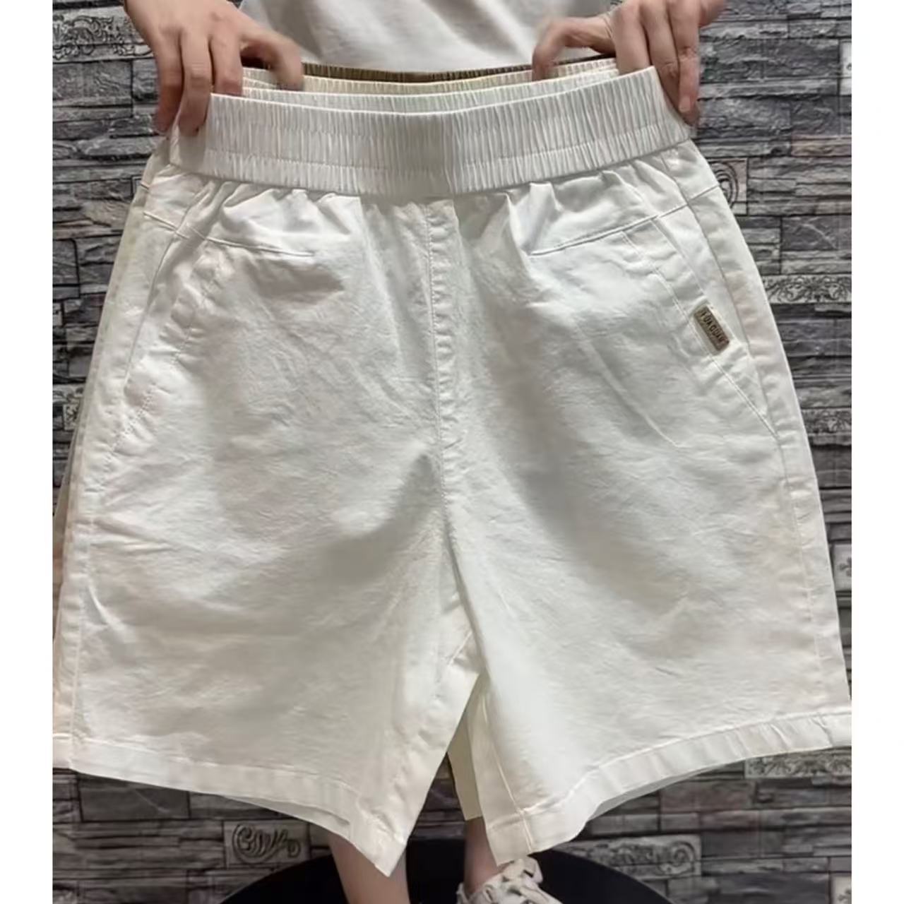 Beige loose shorts back view showing welt pockets and side seam tab