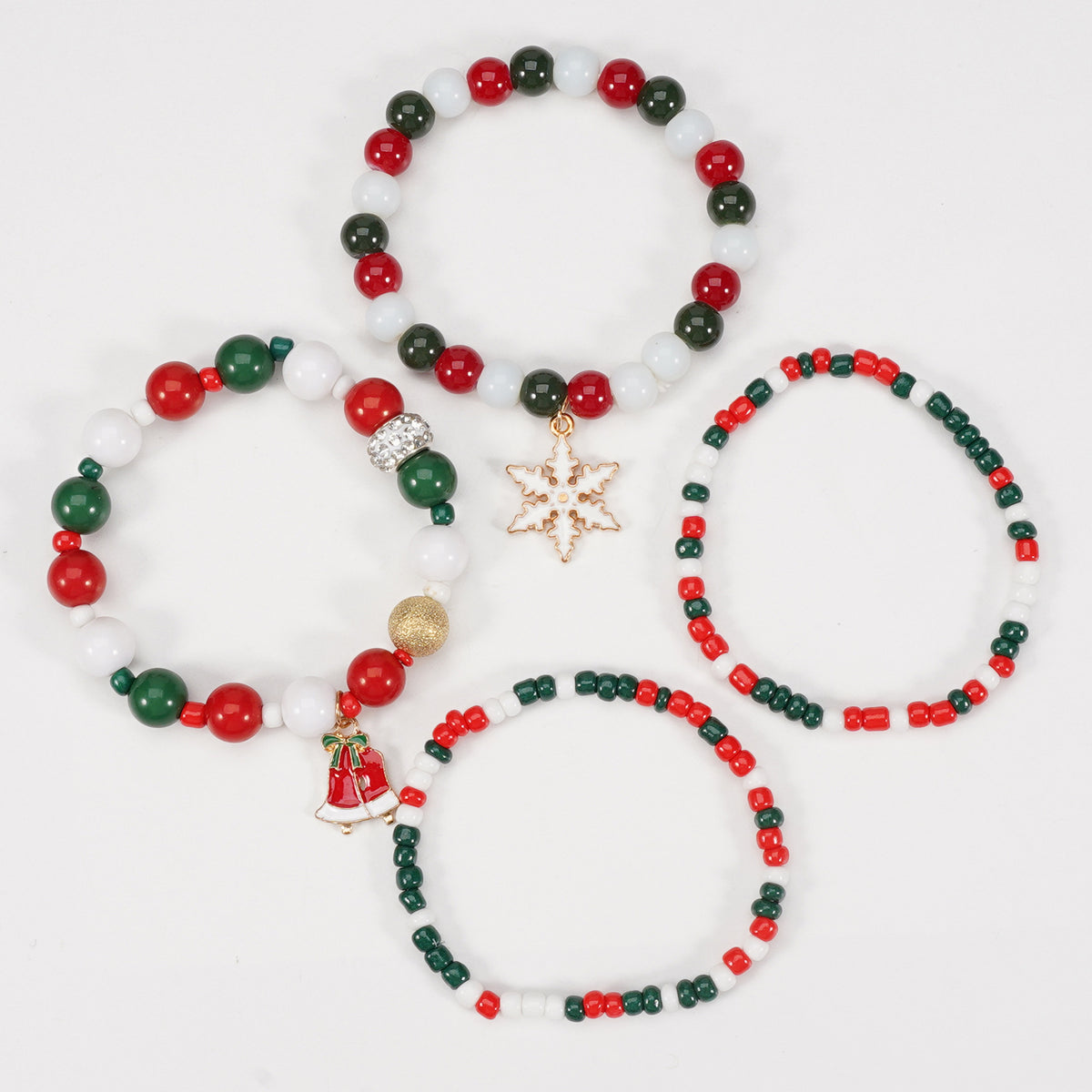 Flat lay of four mixed color bead stretch bracelets, one with a snowflake charm and one with a bell charm