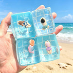 Clear TPR squishy sensory toys with tiny swimmers inside on a beach backdrop