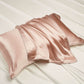 Pink mulberry silk pillowcase with a piped edge on a white bed