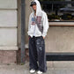 Full length street look of the gray zip up hooded sweatshirt worn with baggy washed wide leg jeans