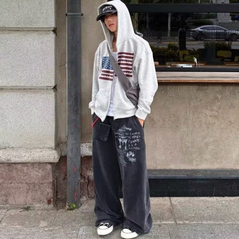 Full length street look of the gray zip up hooded sweatshirt worn with baggy washed wide leg jeans