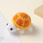 Crocheted orange and yellow shell white turtle, handmade wool charm on a cream surface
