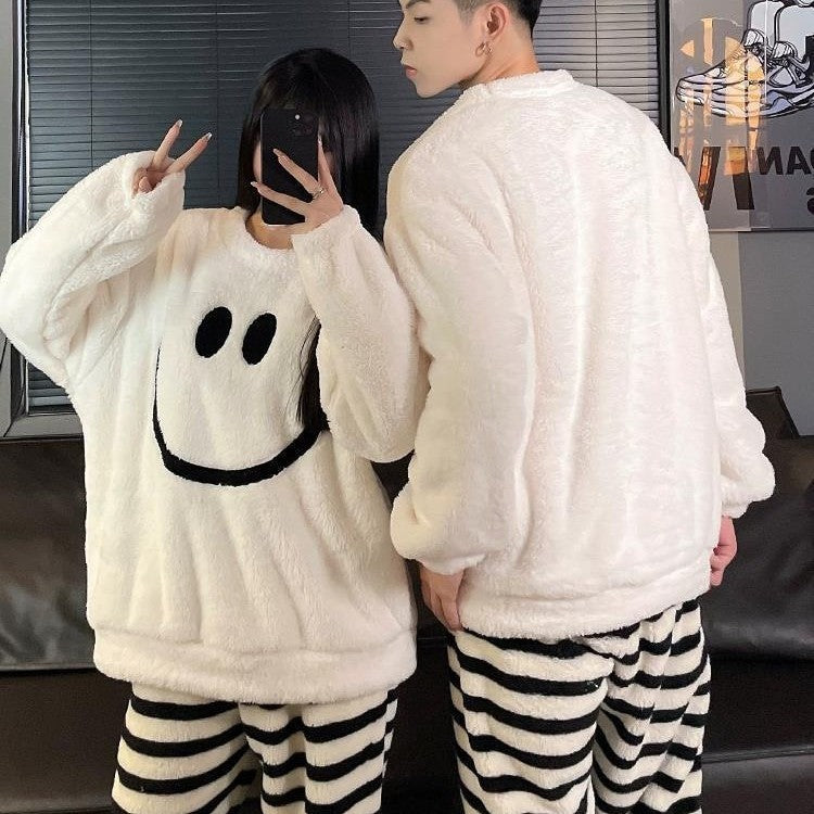 Back of the man's white fleece pullover beside the woman's smiley face top and striped trousers