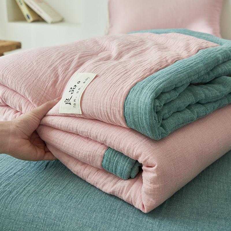 Fresh blue reversible gauze summer quilt folded at the foot of a bed