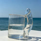Clear glass novelty mug shown from the side to show the straight cup and sculpted handle