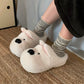 Woman in striped socks wearing white puppy face plush slippers on a woven rug