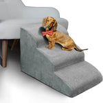 Dachshund in a red bow tie sitting on gray foam pet stairs beside a light sofa