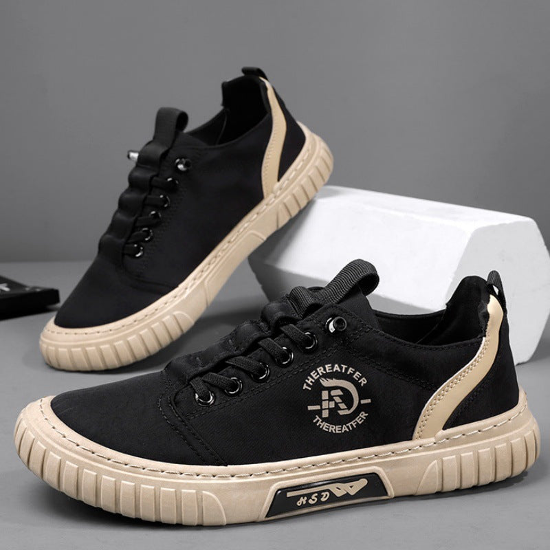 Pair of black lace up canvas sneakers with a beige sole, one shoe tilted against a white block