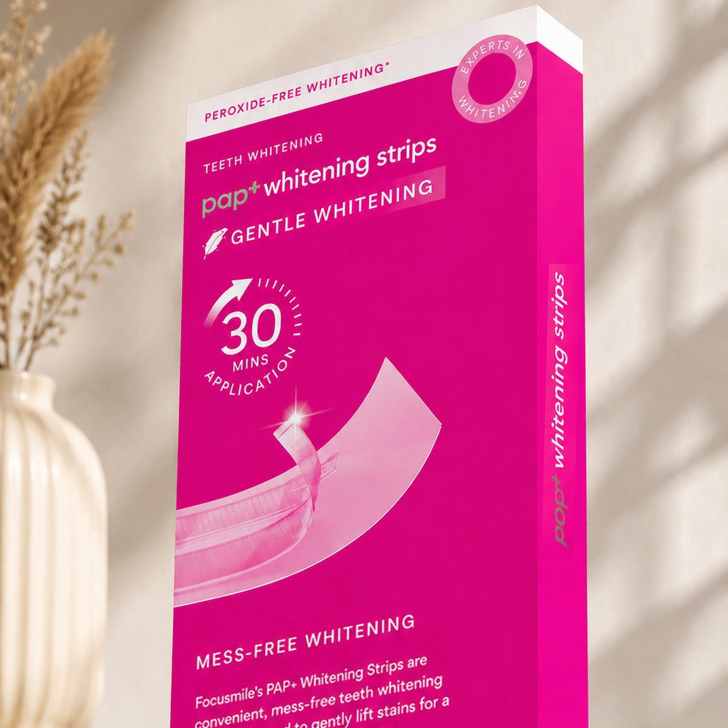 Pink Focusmile PAP+ whitening strips carton beside a ribbed vase and dried pampas grass