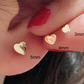 Mini heart gold stud earring next to a hand to show the small millimetre size