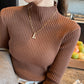 Woman wearing a slim ribbed semi high mock neck knit sweater as a fitted base layer