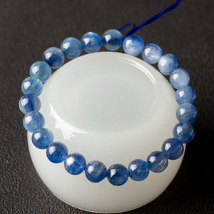 Bracelet strung from natural blue kyanite round gemstone beads resting on a white dish