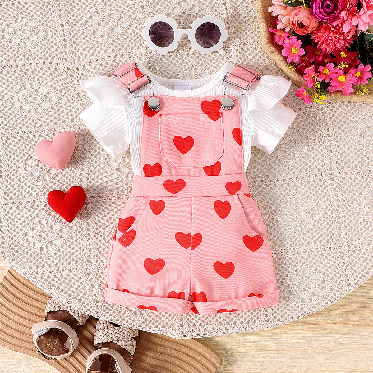 Baby girls two piece set with ribbed flutter sleeve top and printed suspender overall shorts on a knit backdrop