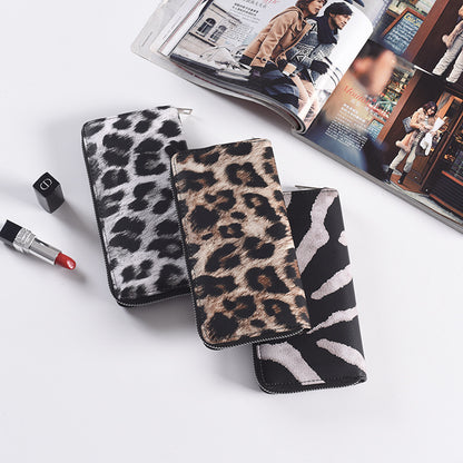 Animal print zip around long wallet in leopard and zebra prints on a white surface