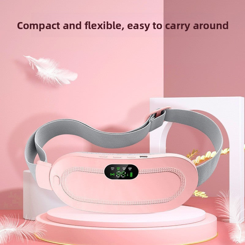 Pink cordless heating belt with a grey adjustable strap and a lit green LED display on a pink podium