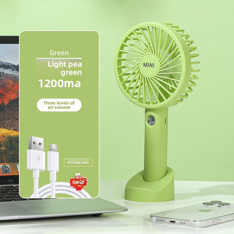 USB rechargeable handheld fan running hands free on a desk while charging