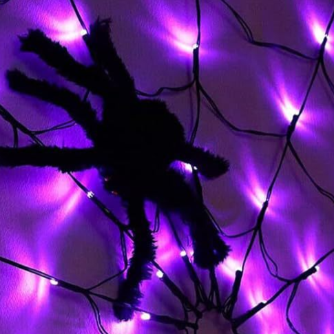 Purple lit spider web net light with a large black furry spider prop at the center