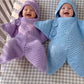 Purple and blue crochet star baby buntings with hoods worn by babies in a checked crib