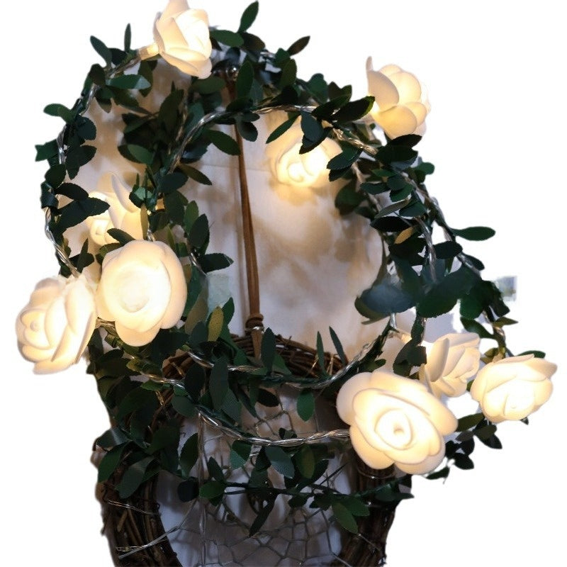 Decorative LED flower fairy string lights on a green leaf vine glowing warm, lifestyle photo