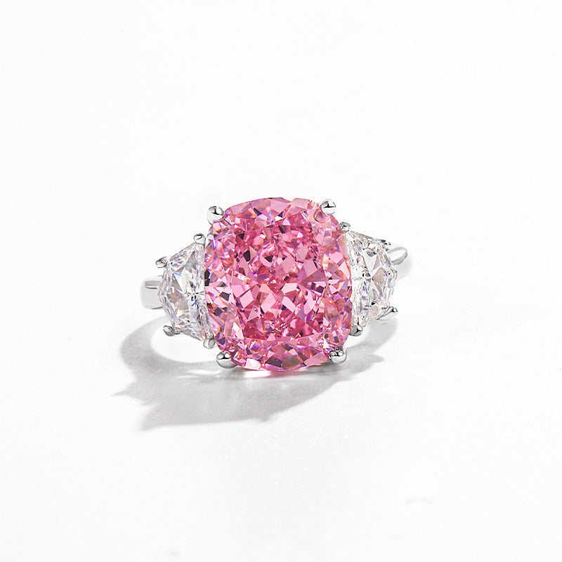 Cushion cut pink simulated diamond ring flanked by two clear trillion side stones, plain white background