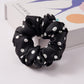 Several solid color satin scrunchies grouped together