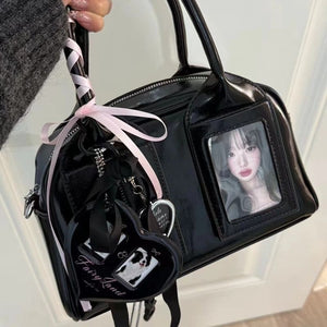 Black glossy crossbody bag with top handles, a zip top and a photo card in the clear front window