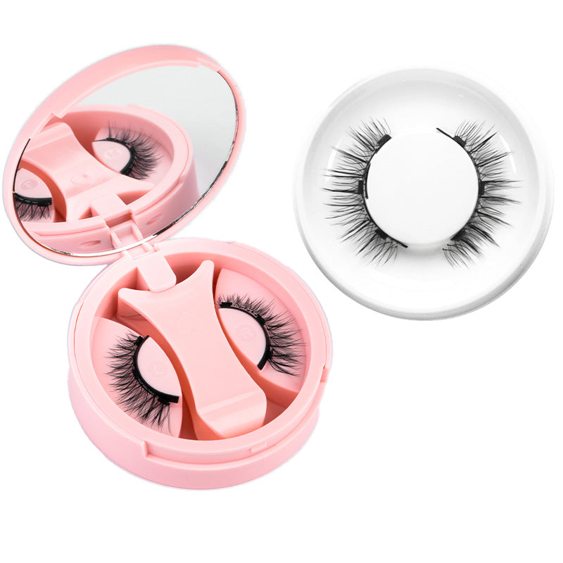 Pink round magnetic lash case open beside a fluttery black magnetic lash in a ring